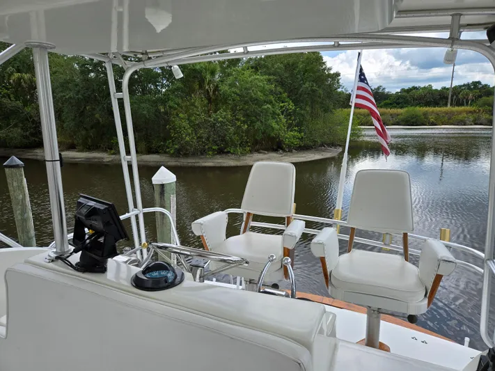 Bad To The Bone Yacht Photos Pics 1995 Egg Harbor Golden Egg 42 yacht interior with helm chairs and American flag on a serene river.