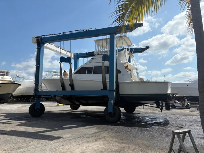Bad To The Bone Yacht Photos Pics 1995 Egg Harbor Golden Egg 42 yacht lifted by a boat hoist under a sunny sky.