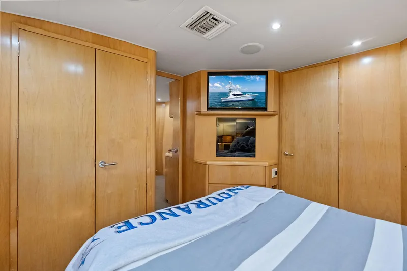 Endurance Yacht Photos Pics Interior of 1998 Hatteras 60 Convertible yacht bedroom with TV and wooden cabinetry.