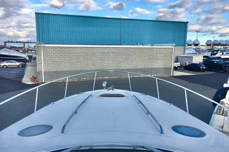  Yacht Photos Pics 2007 Sea Ray 340 Sundancer yacht docked near a blue warehouse under a cloudy sky.