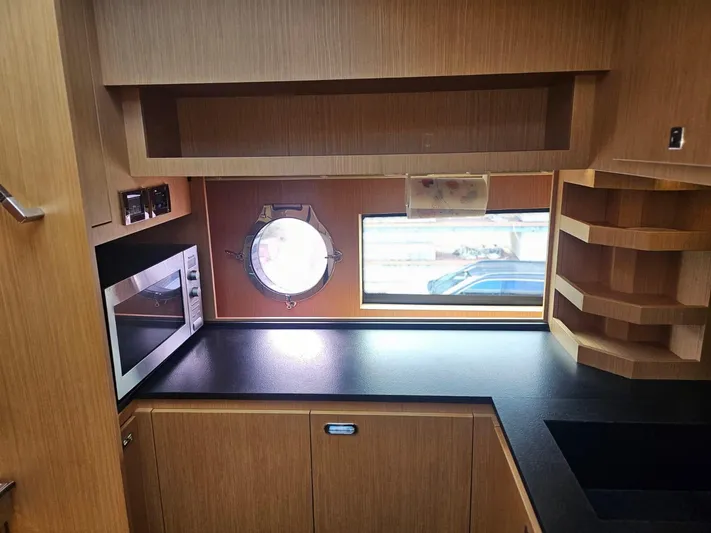  Yacht Photos Pics Modern kitchen interior of 2016 Riva 88' Domino Super yacht with microwave and porthole.