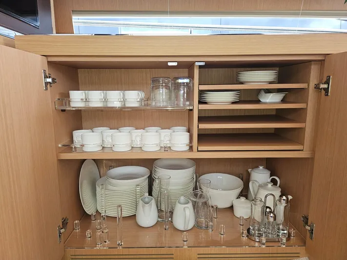  Yacht Photos Pics Luxurious yacht kitchen cabinet with neatly arranged white dishes and glassware, Riva 88' Domino Super 2016.