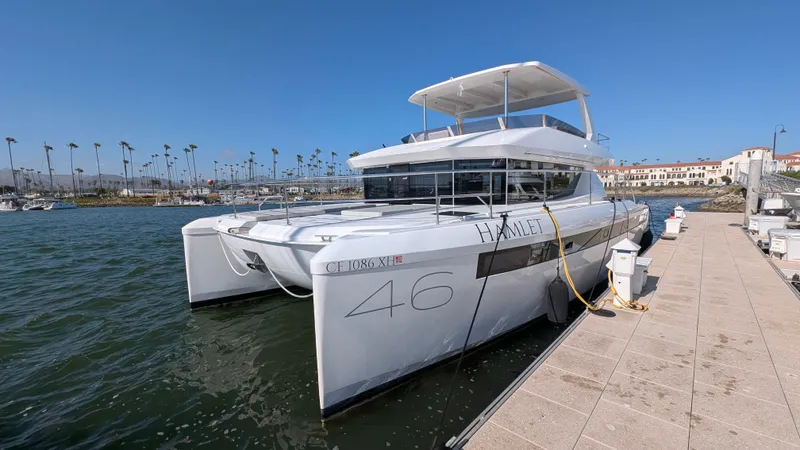 Hamlet Yacht Photos Pics 2023 Leopard Powercat 46 docked at marina, clear sky, palm trees in background.