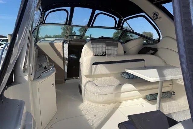 Wet Mess Yacht Photos Pics 2004 Sea Ray 360 Sundancer interior with seating, table, and helm, under a clear blue sky.