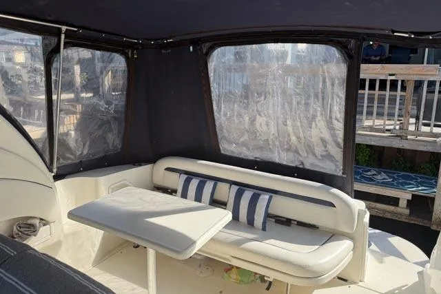 Wet Mess Yacht Photos Pics Interior of 2004 Sea Ray 360 Sundancer with seating and table, enclosed by clear panels.