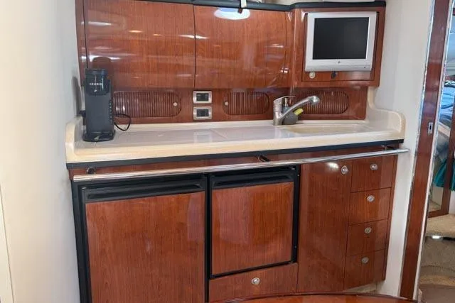 Wet Mess Yacht Photos Pics 2004 Sea Ray 360 Sundancer yacht interior with kitchenette, wood cabinetry, and built-in TV.