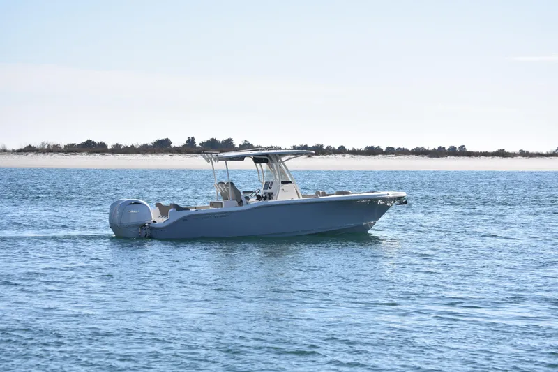 Yacht Photos Pics 2024 Key West 263 FS boat cruising on calm blue waters near a sandy shoreline.