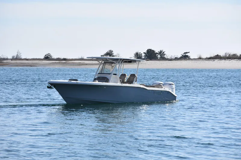  Yacht Photos Pics 2024 Key West 263 FS boat cruising on calm waters near a sandy shoreline.
