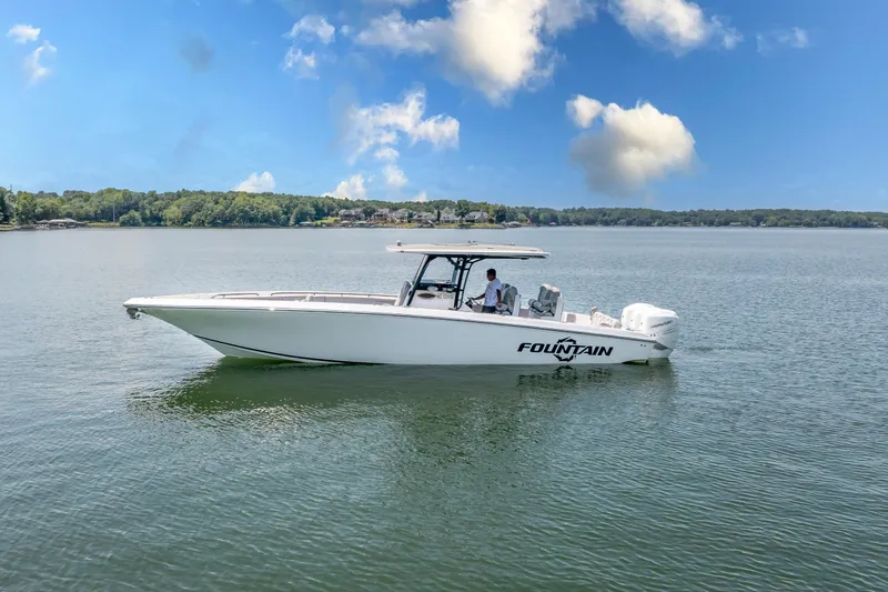  Yacht Photos Pics 2023 Fountain 38 SC boat cruising on a serene lake under a clear blue sky.