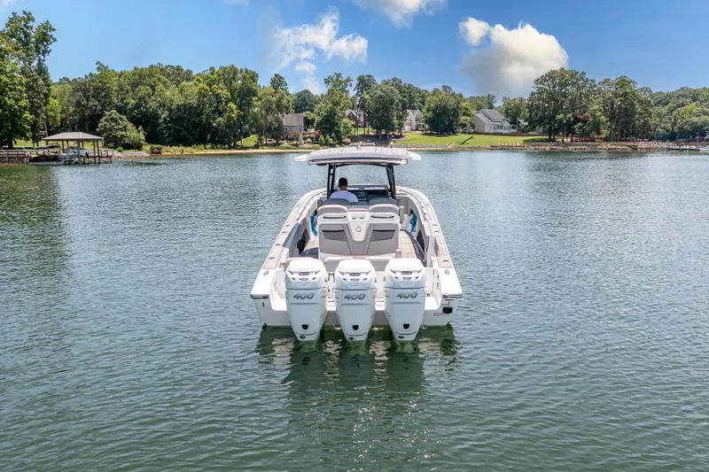  Yacht Photos Pics 2023 Fountain 38 SC boat on a serene lake with lush greenery.