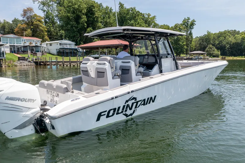  Yacht Photos Pics 2023 Fountain 38 SC boat on a serene lake with lush greenery.