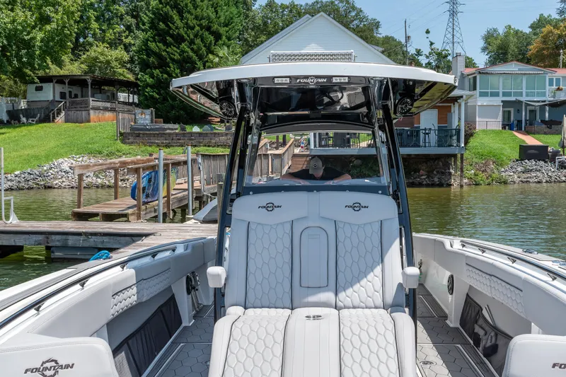  Yacht Photos Pics 2023 Fountain 38 SC boat docked by a lakeside house, showcasing luxury seating and design.