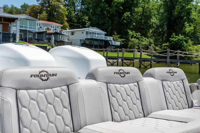  Yacht Photos Pics 2023 Fountain 38 SC boat seats with logo, docked near waterfront homes and lush greenery.