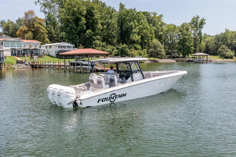  Yacht Photos Pics 2023 Fountain 38 SC boat cruising on a serene lake near waterfront homes.