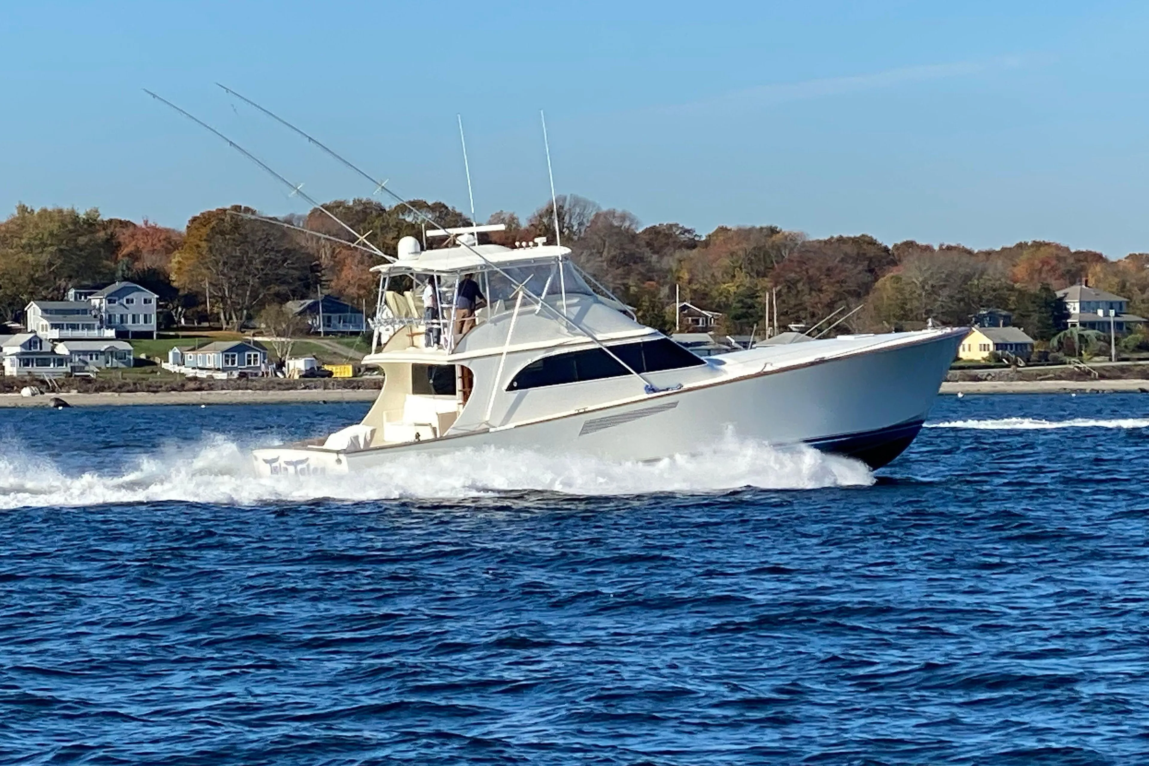1999 Hines-Farley SPORTFISHERMAN cruising on water near coastal homes.