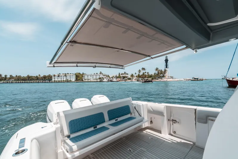  Yacht Photos Pics 2021 Intrepid 407 Nomad SE boat with canopy, ocean view, and distant lighthouse.
