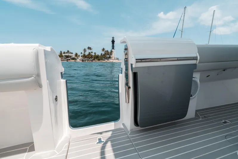  Yacht Photos Pics 2021 Intrepid 407 Nomad SE boat with open side door, ocean view, and distant lighthouse.