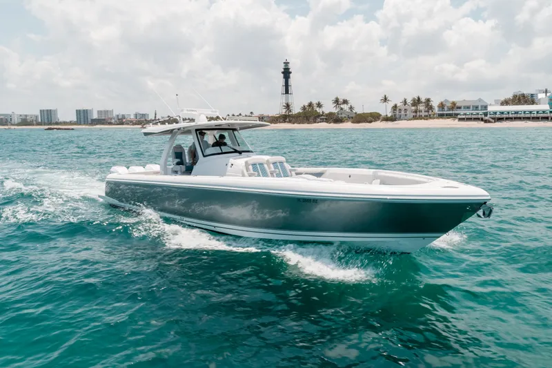  Yacht Photos Pics 2021 Intrepid 407 Nomad SE cruising on turquoise ocean near a lighthouse.