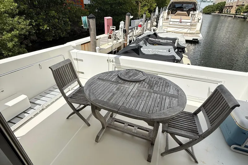 The Motley Crew Yacht Photos Pics Outdoor seating on a 2003 Rival 5700 Navigator yacht, docked with jet skis nearby.