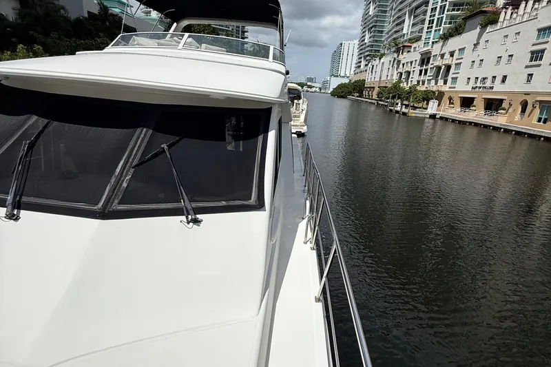 The Motley Crew Yacht Photos Pics 2003 Rival 5700 Navigator yacht cruising along a scenic urban waterway.