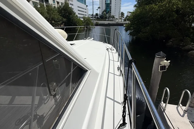 The Motley Crew Yacht Photos Pics 2003 Rival 5700 Navigator yacht docked by waterfront buildings and trees.