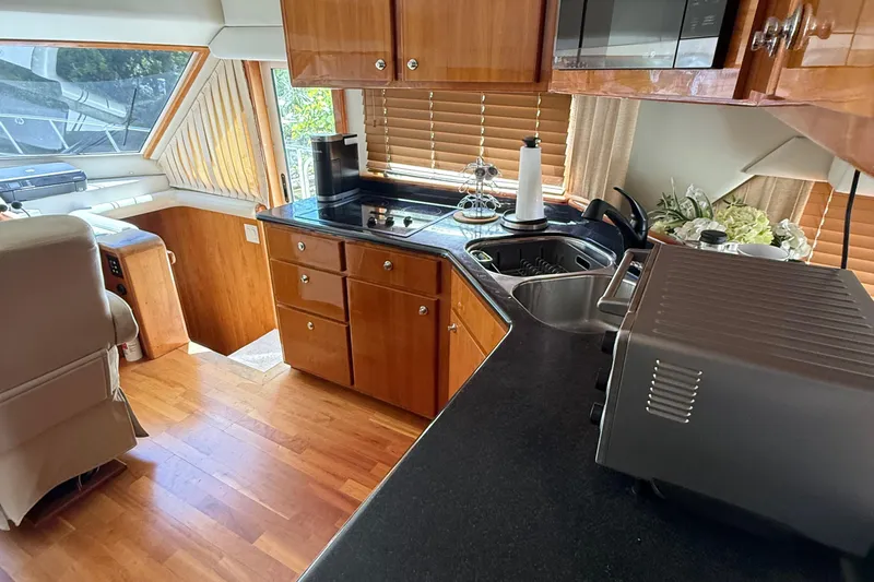 The Motley Crew Yacht Photos Pics Luxurious 2003 Rival 5700 Navigator yacht kitchen with wood cabinetry and modern appliances.