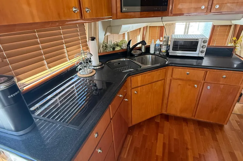 The Motley Crew Yacht Photos Pics 2003 Rival 5700 Navigator kitchen with wooden cabinets, black countertops, and modern appliances.