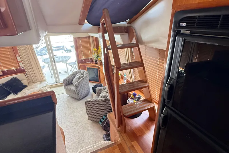 The Motley Crew Yacht Photos Pics Interior of 2003 Rival 5700 Navigator yacht with cozy seating and wooden ladder.