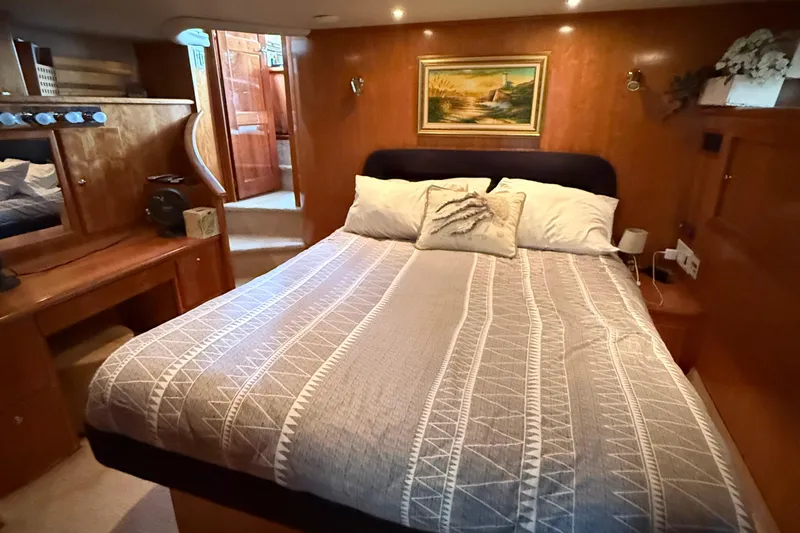 The Motley Crew Yacht Photos Pics Luxurious bedroom interior of 2003 Rival 5700 Navigator yacht with cozy bed and elegant decor.