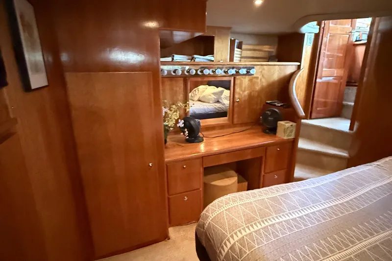 The Motley Crew Yacht Photos Pics Luxurious wooden interior of 2003 Rival 5700 Navigator yacht cabin with vanity and bed.