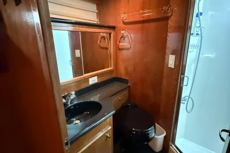 The Motley Crew Yacht Photos Pics Compact bathroom in 2003 Rival 5700 Navigator with wood paneling and modern fixtures.