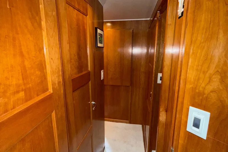 The Motley Crew Yacht Photos Pics Wood-paneled hallway inside a 2003 Rival 5700 Navigator yacht, featuring warm tones and elegant design.