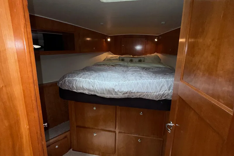 The Motley Crew Yacht Photos Pics Cozy cabin interior of 2003 Rival 5700 Navigator with wooden finish and comfortable bedding.
