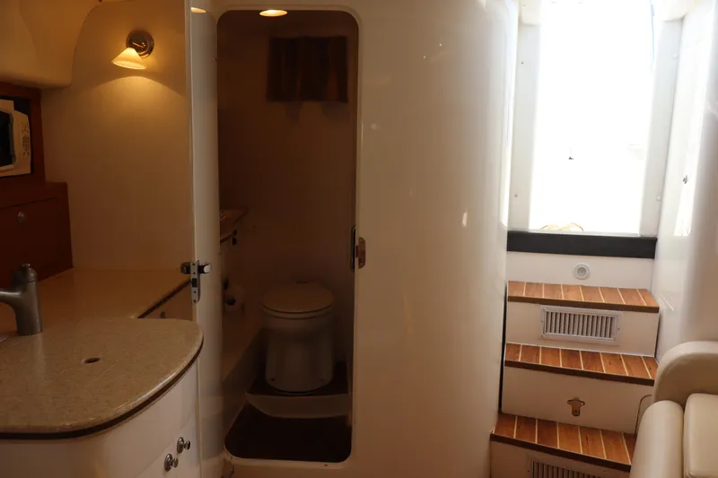 Good Karma Yacht Photos Pics Interior of 2006 Intrepid 377 Walk Around boat, featuring a compact bathroom and wooden steps.
