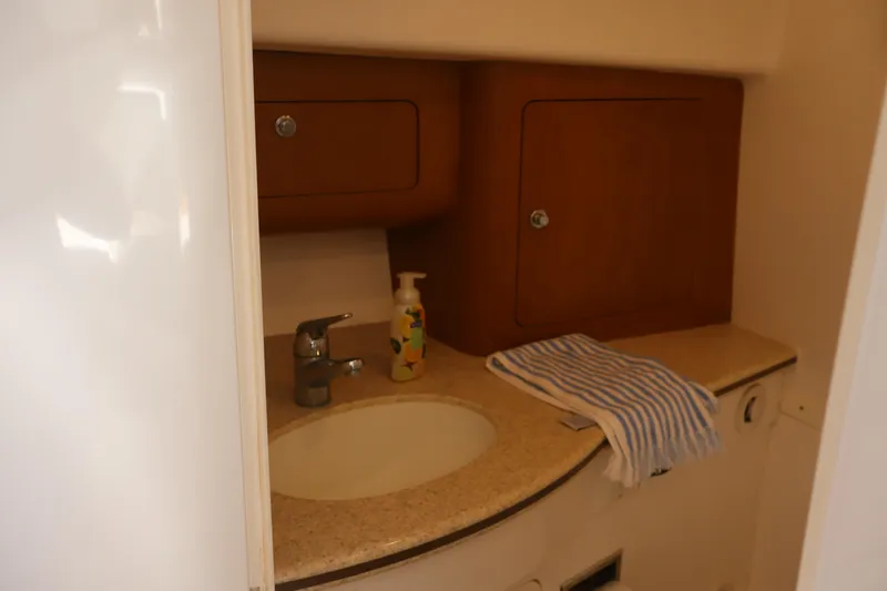 Good Karma Yacht Photos Pics 2006 Intrepid 377 Walk Around boat bathroom with sink, cabinets, and striped towel.
