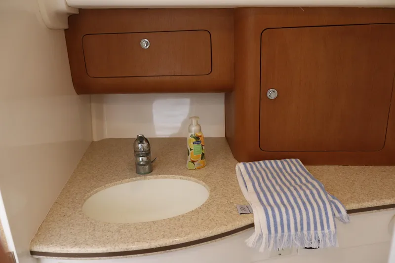 Good Karma Yacht Photos Pics 2006 Intrepid 377 Walk Around boat interior with sink, wooden cabinets, and striped towel.