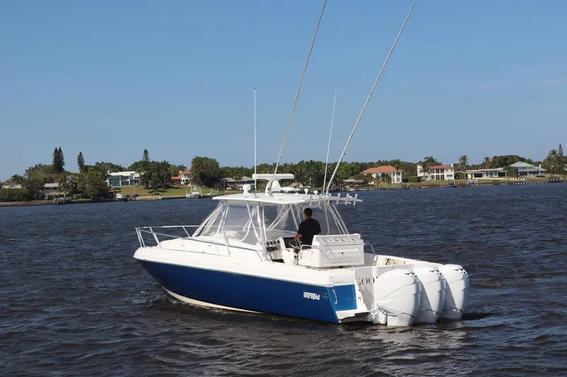 Good Karma Yacht Photos Pics 2006 Intrepid 377 Walk Around boat on water with triple engines, blue hull, and clear sky.