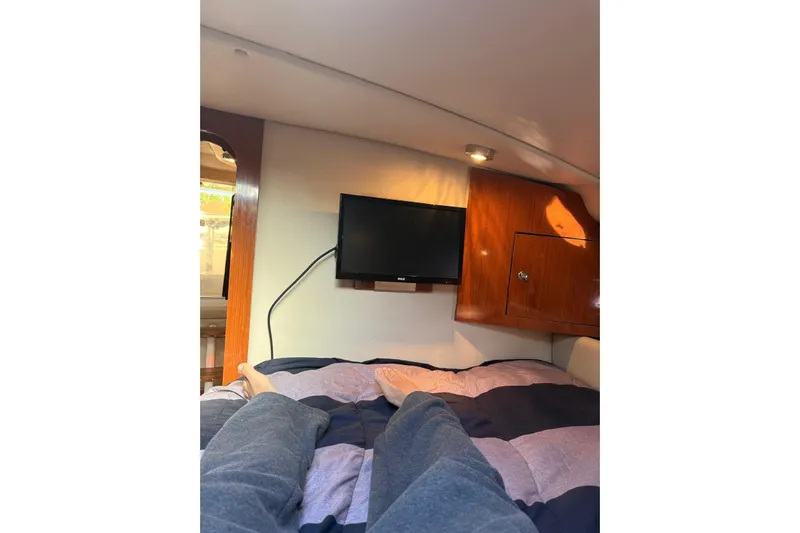 Borabora III Yacht Photos Pics Interior of 2007 Regal Commodore 3760 IB with bed, TV, and wooden cabinet.