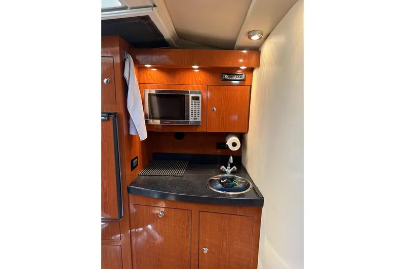 Borabora III Yacht Photos Pics 2007 Regal Commodore 3760 IB yacht kitchenette with microwave, sink, and wooden cabinetry.