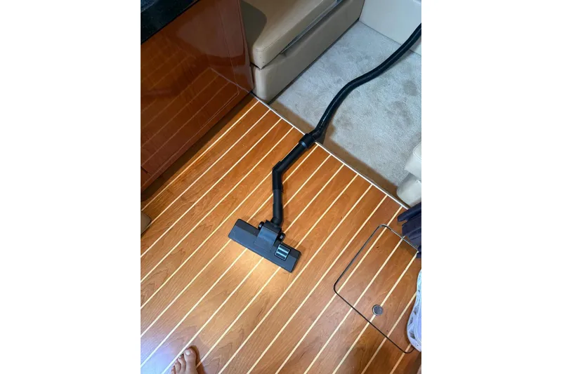Borabora III Yacht Photos Pics Vacuuming wooden floor inside 2007 Regal Commodore 3760 IB boat cabin.