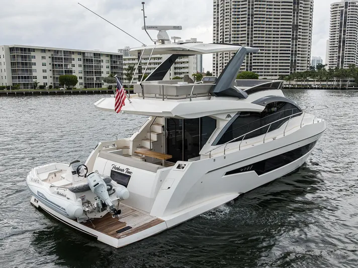 Harbour Time Yacht Photos Pics 2021 Astondoa 52 yacht cruising near modern waterfront buildings.