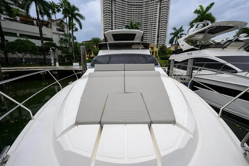 Harbour Time Yacht Photos Pics Luxurious 2021 Astondoa 52 yacht with spacious sunbathing deck, docked near palm trees and high-rise buildings.