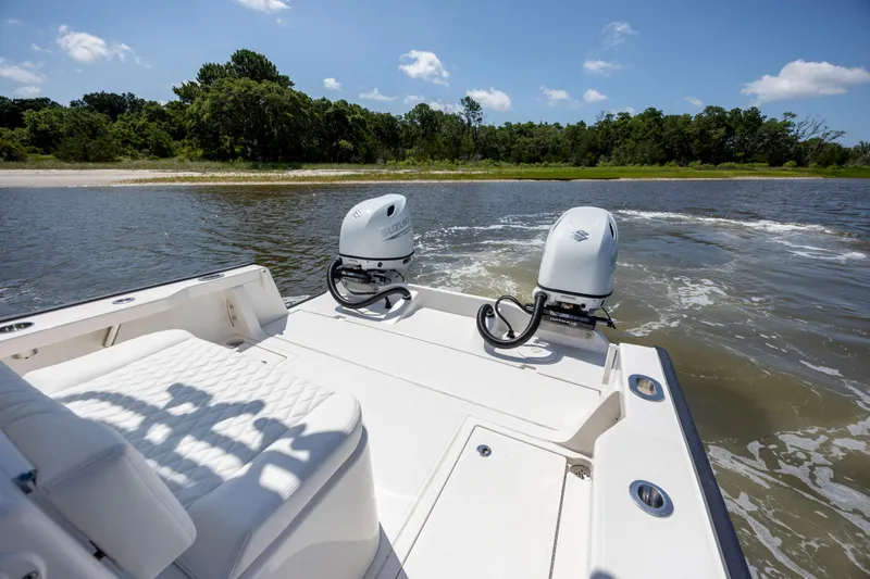  Yacht Photos Pics Calcutta 263 boat with dual Suzuki engines on a sunny day near a shoreline.