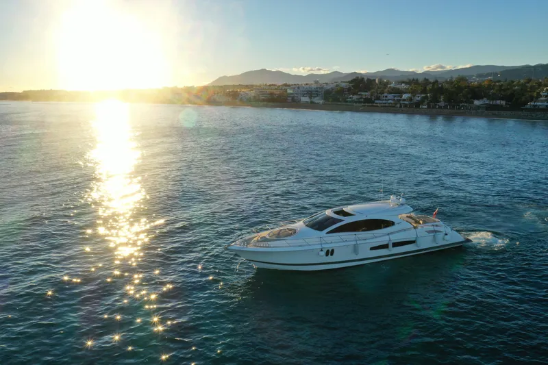 Carbon Copy V Yacht Photos Pics 2009 Lazzara LSX 75 yacht cruising at sunset near coastal cityscape.