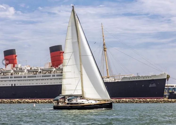 Blue Sky Yacht Photos Pics Sailboat Beneteau Sense 50 (2012) cruising near a large ocean liner.