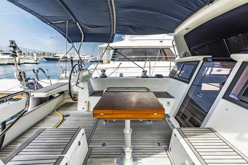 Blue Sky Yacht Photos Pics 2012 Beneteau Sense 50 yacht cockpit with wooden table and steering wheel, docked at marina.