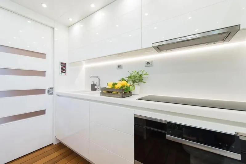  Yacht Photos Pics Modern kitchen interior on 2015 Maiora 24S yacht, featuring sleek white cabinetry and appliances.