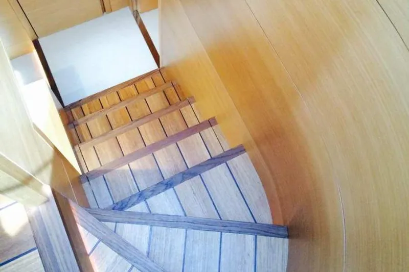  Yacht Photos Pics Wooden staircase inside 2015 Maiora 24S yacht, featuring elegant curved design.
