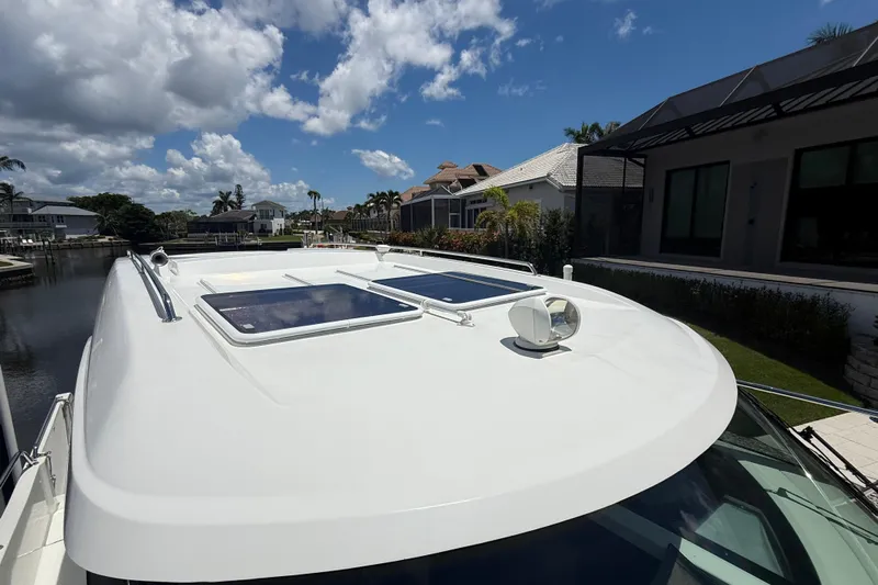  Yacht Photos Pics 2024 Beneteau Antares 11 boat roof with skylights, docked by waterfront homes.