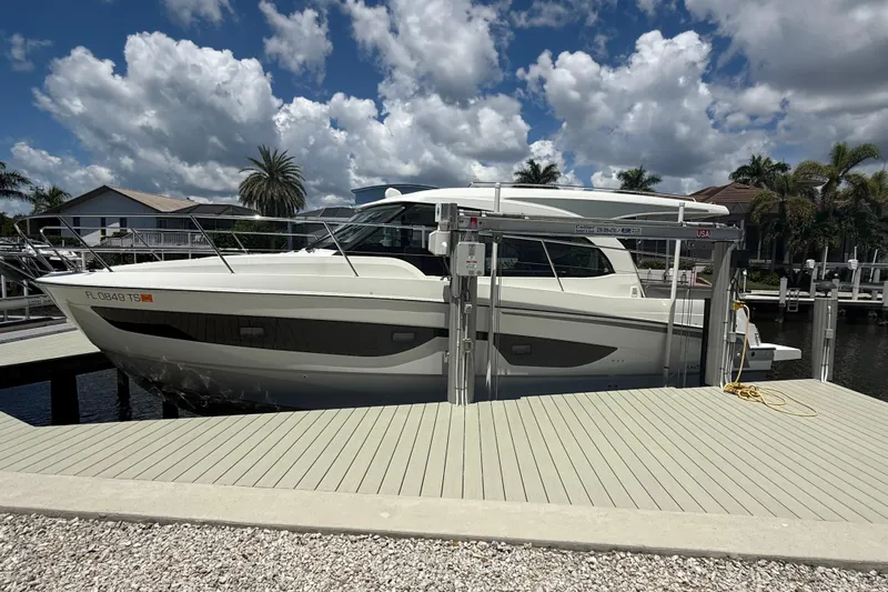  Yacht Photos Pics 2024 Beneteau Antares 11 docked under a cloudy sky, surrounded by palm trees.